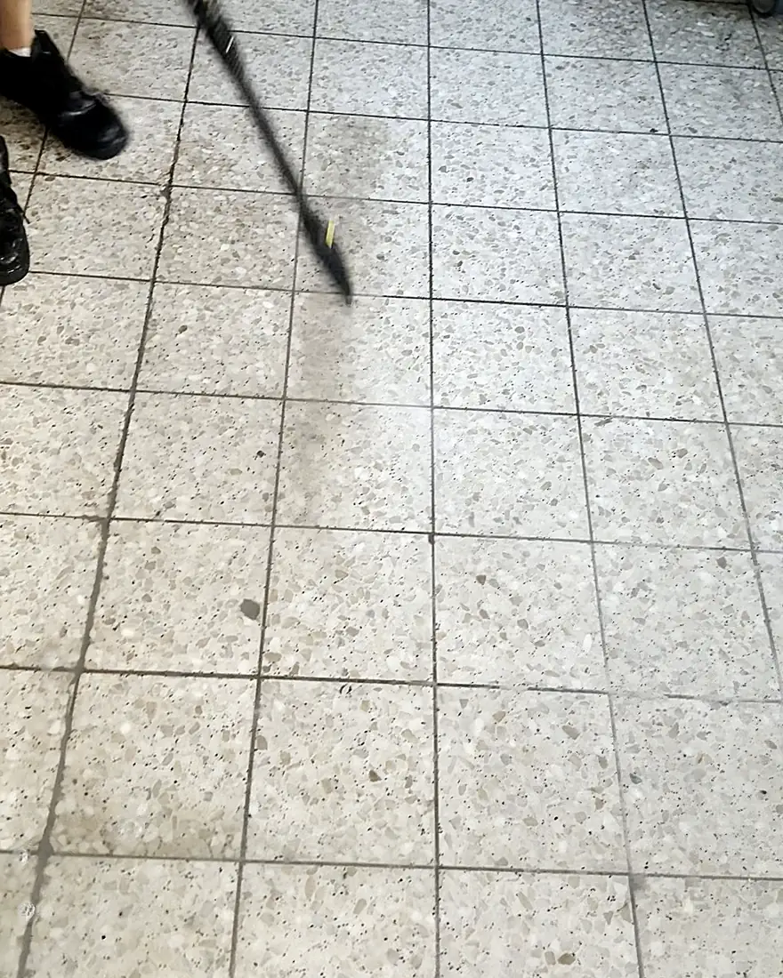Hochdruckreinigung: eine helle, saubere Spur zieht sich durch den grauen Schmutzfilm eines Küchenbodens